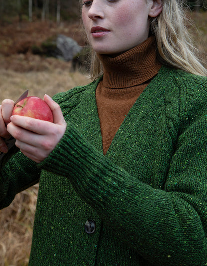 Person wearing a donegal tweed green knitted cardigan and hat in a natural setting