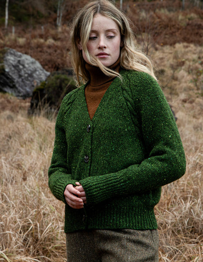 Person wearing a donegal tweed green knitted cardigan and hat in a natural setting