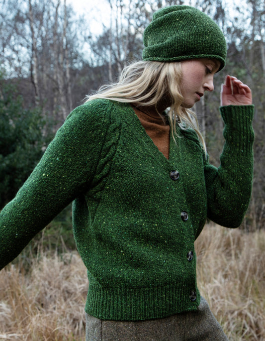 Person wearing a donegal tweed green knitted cardigan and hat in a natural setting