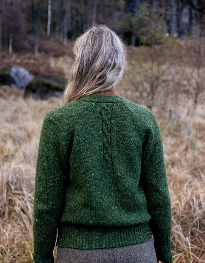 Person wearing a donegal tweed green knitted cardigan and hat in a natural setting