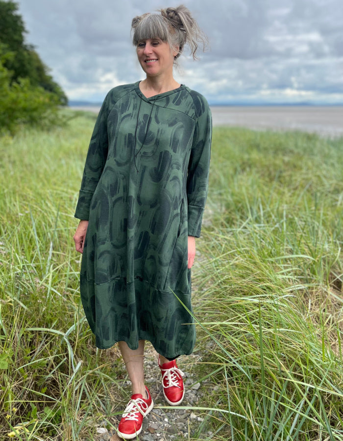 green jersey midi length bubble shaped dress with full length sleeves and pockets, graphic swirl print on the fabric