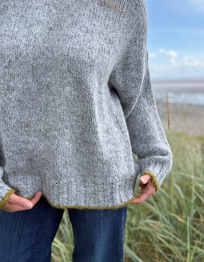 woman wearing cosy grey turtle neck sweater on a beach