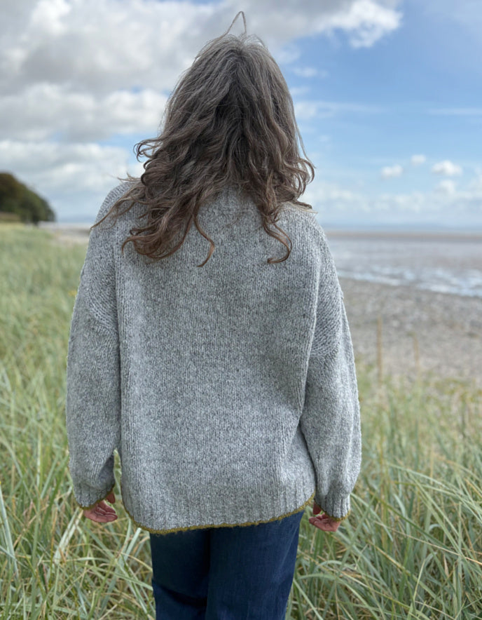 woman wearing cosy grey turtle neck sweater on a beach