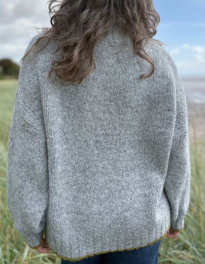 woman wearing cosy grey turtle neck sweater on a beach