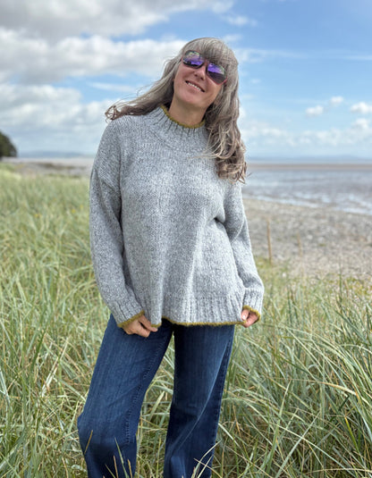 woman wearing cosy grey turtle neck sweater on a beach