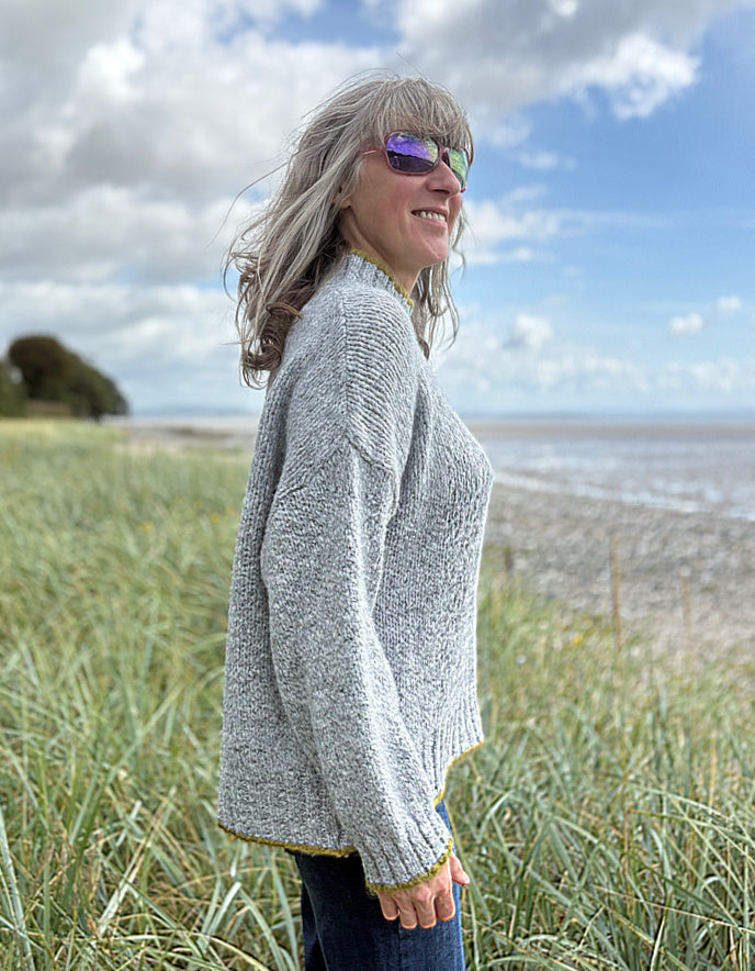 woman wearing cosy grey turtle neck sweater on a beach
