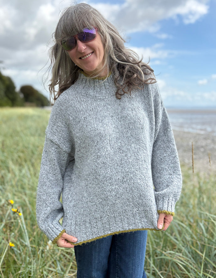 woman wearing cosy grey turtle neck sweater on a beach