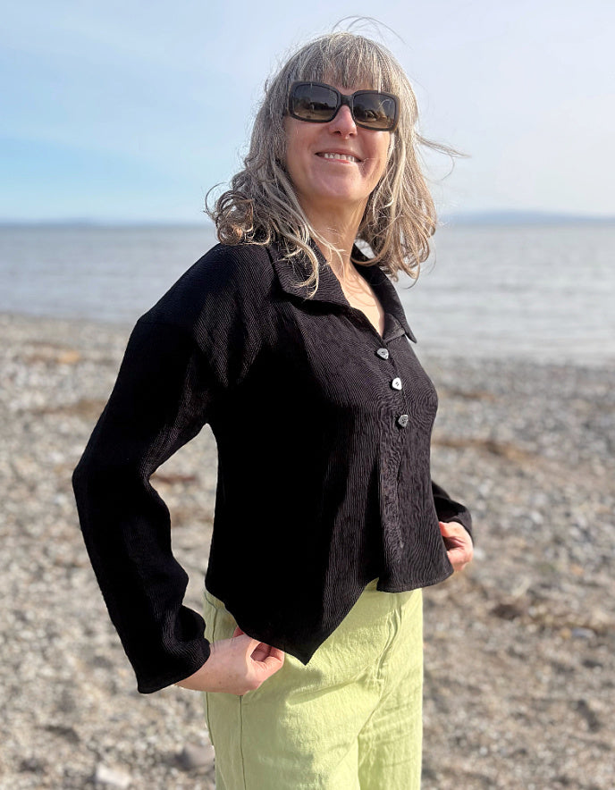 Woman wearing a black jacket and sunglasses on a beach