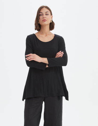 Woman wearing a black long-sleeve top and pants on a white background