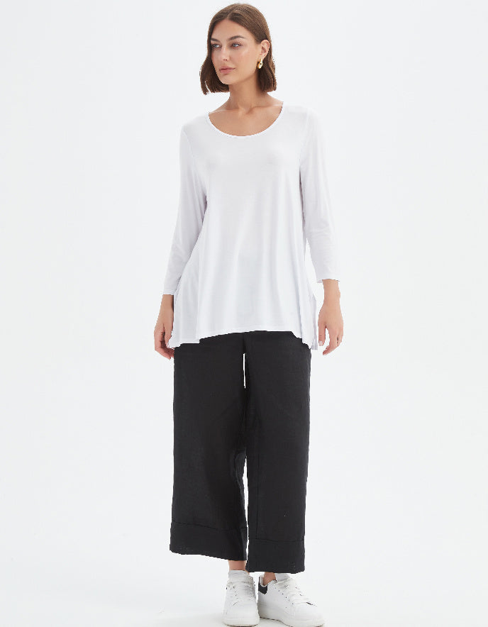 Woman wearing a white top and black pants on a white background