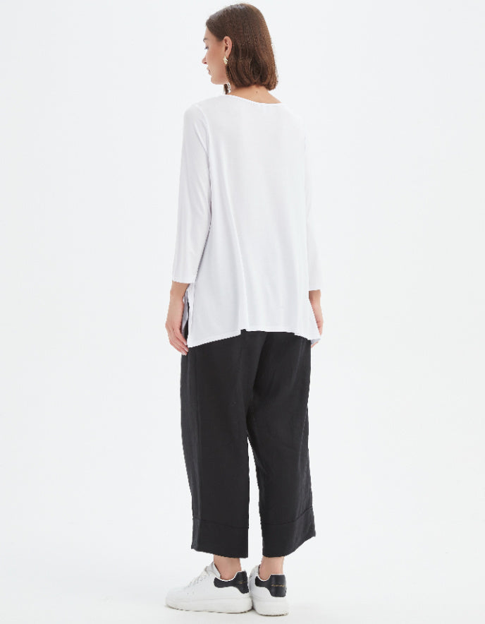 Person wearing a white top and black pants on a white background