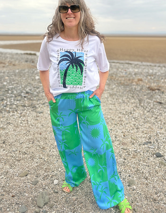 silky palazzo trousers with elasticated waist and wide leg in green and blue palm tree print