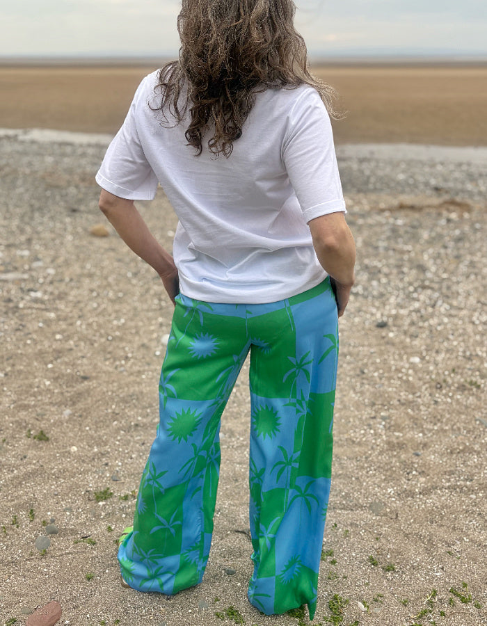 silky palazzo trousers with elasticated waist and wide leg in green and blue palm tree print