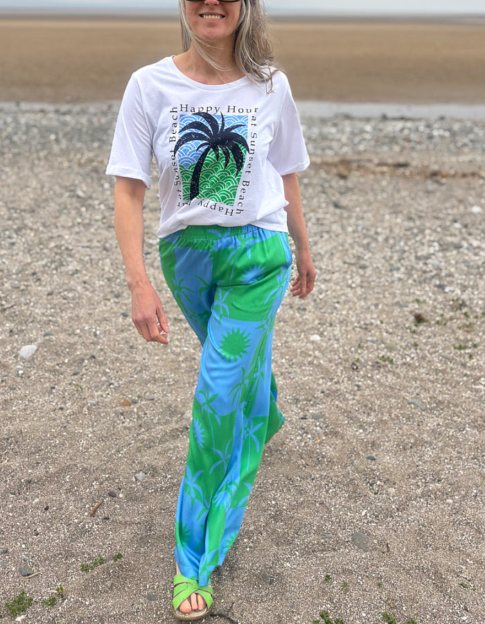 silky palazzo trousers with elasticated waist and wide leg in green and blue palm tree print