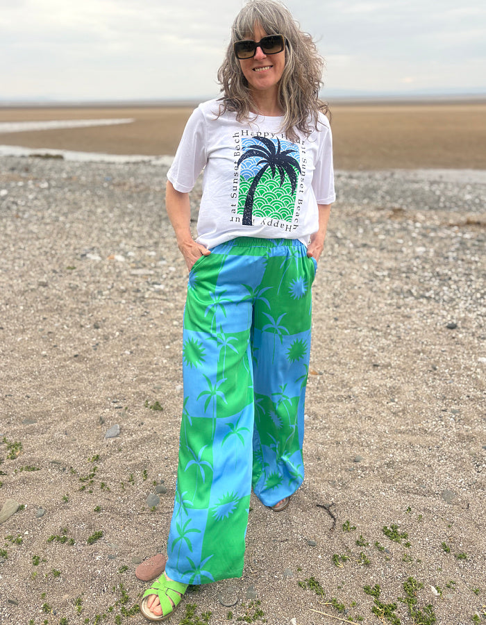 silky palazzo trousers with elasticated waist and wide leg in green and blue palm tree print