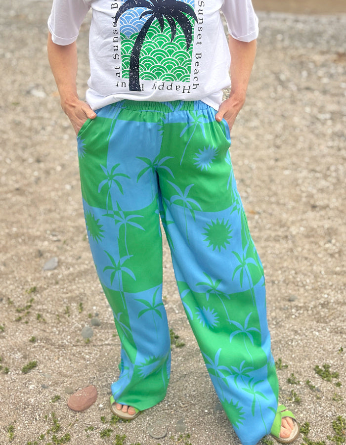 silky palazzo trousers with elasticated waist and wide leg in green and blue palm tree print