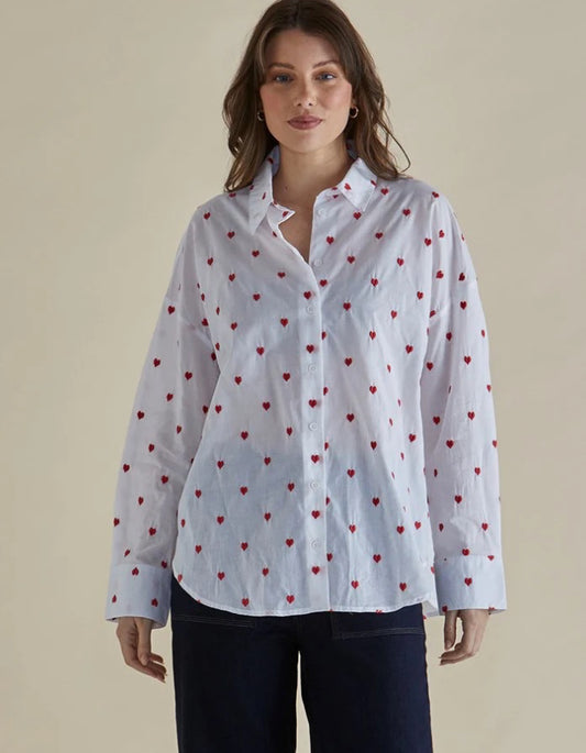 Woman wearing a white shirt with red heart patterns on a beige background