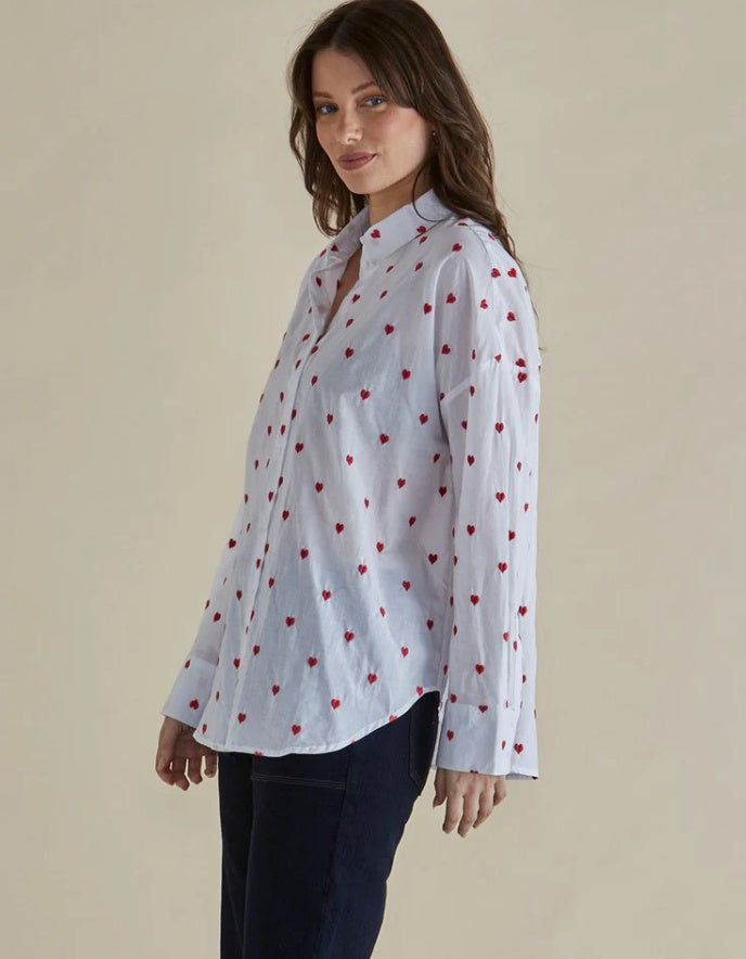 Woman wearing a white shirt with red heart patterns on a beige background