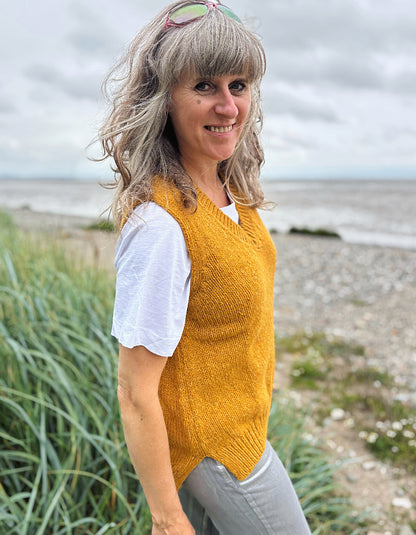 Woman wearing a yellow knitted vest on a beach