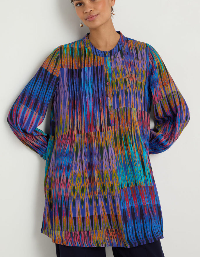 Multicolored patterned top worn by a person against a white background