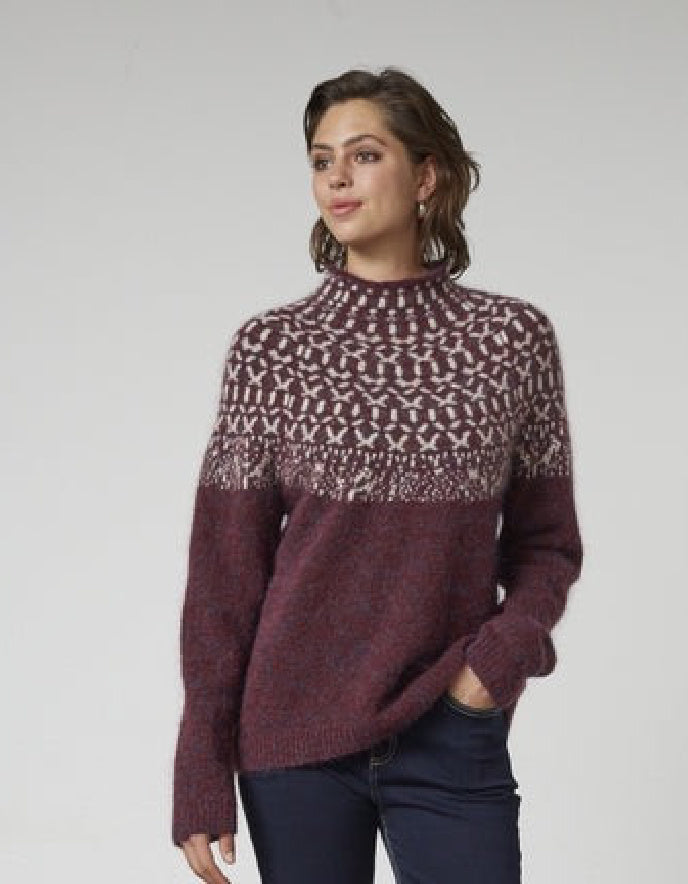 Woman wearing a patterned sweater on a plain background