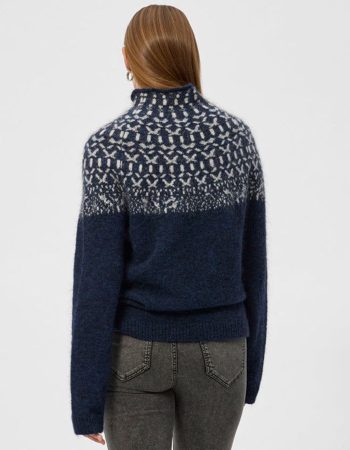 Woman wearing an Icelandic patterned navy sweater on a white background