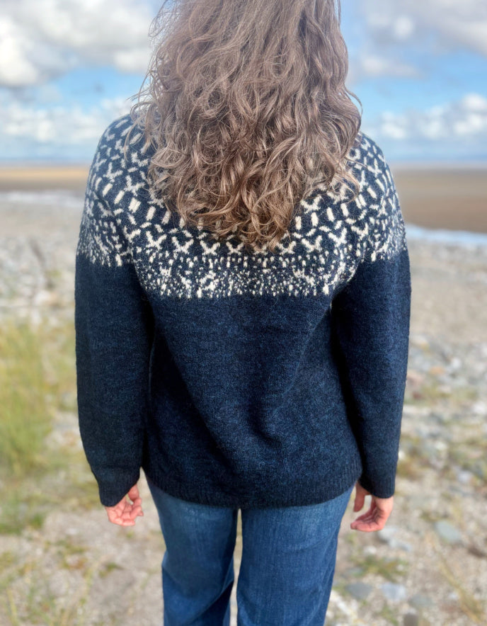 Woman wearing an Icelandic patterned navy sweater on a white background