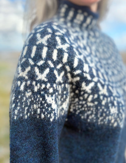 Close-up of a blue sweater with white pattern, blurred background