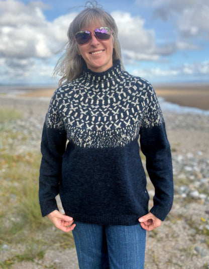 Woman wearing an Icelandic patterned navy sweater on a white background