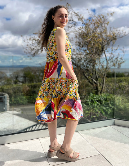 sleeveless cotton sundress with bright coloured print in collage style, tiered skirt and two front patch pockets