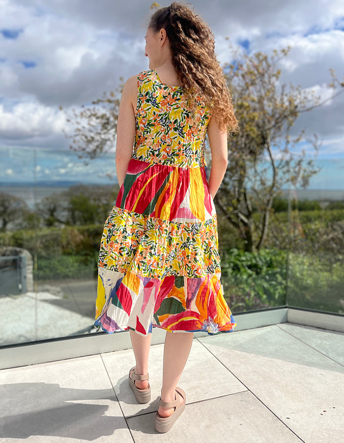 sleeveless cotton sundress with bright coloured print in collage style, tiered skirt and two front patch pockets