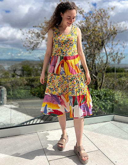 sleeveless cotton sundress with bright coloured print in collage style, tiered skirt and two front patch pockets