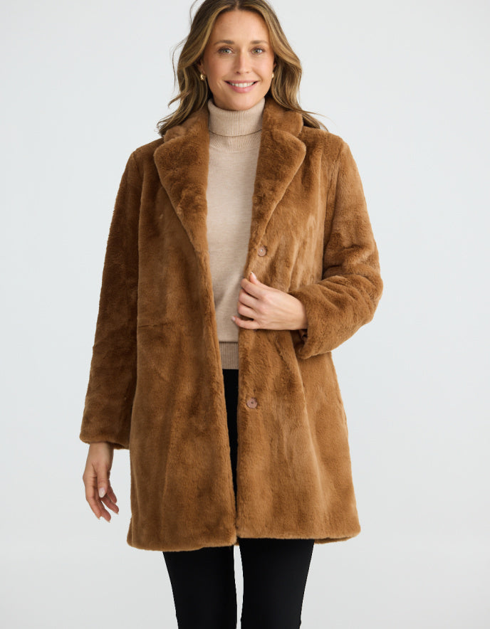 Woman wearing a brown faux fur coat on a white background