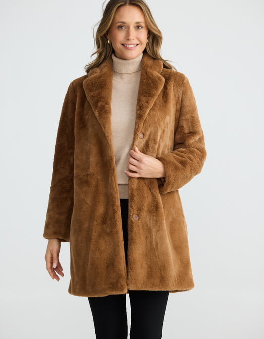 Woman wearing a brown faux fur coat on a white background
