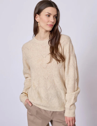Woman wearing a beige sweater against a white background