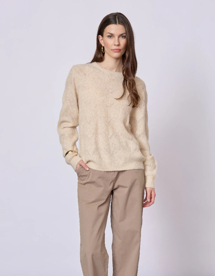 Woman wearing a beige sweater and pants on a white background