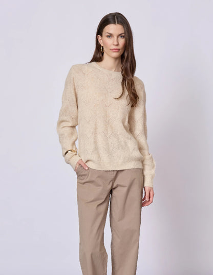 Woman wearing a beige sweater and pants on a white background