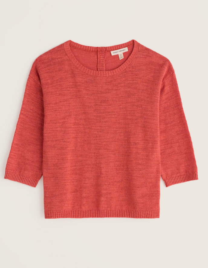 Person wearing a coral red cotton sweater and burgundy pants on a white background