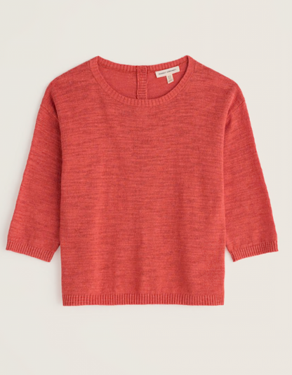 Person wearing a coral red cotton sweater and burgundy pants on a white background