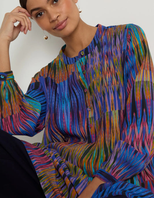 Woman wearing a colorful patterned dress against a plain background