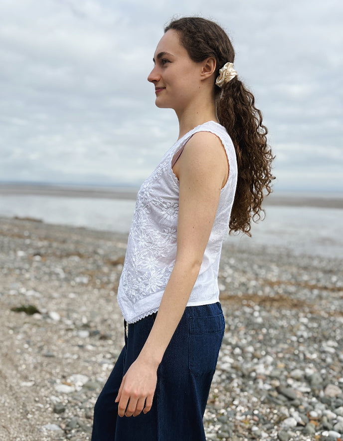 Woman standing on a pebbly beach with ocean in the background