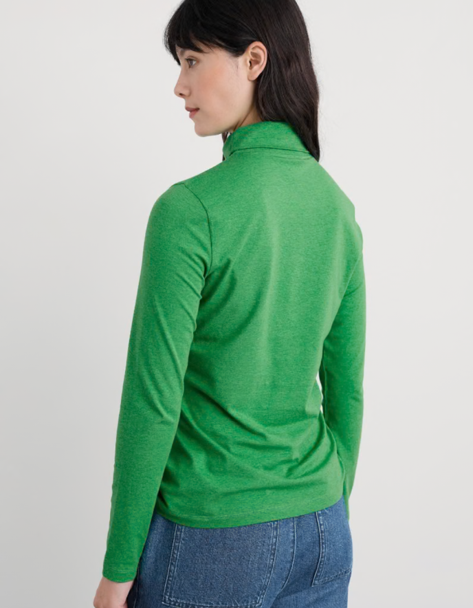 Person wearing a green long-sleeve top on a plain background