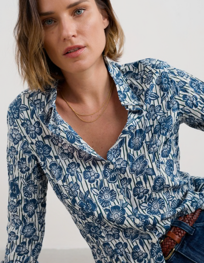 Woman wearing a blue floral patterned shirt against a plain background