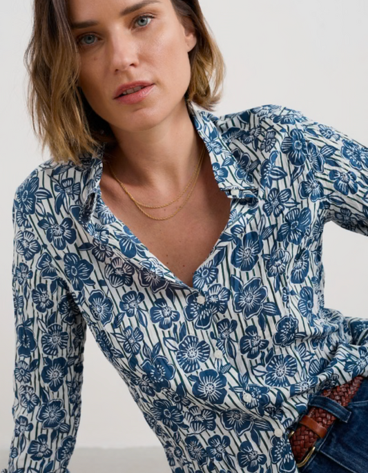 Woman wearing a blue floral patterned shirt against a plain background