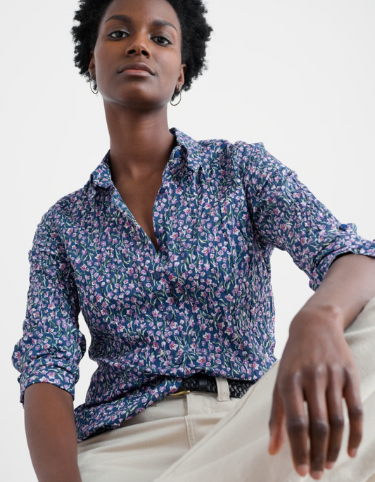 Woman wearing a floral blouse with rolled-up sleeves against a white background