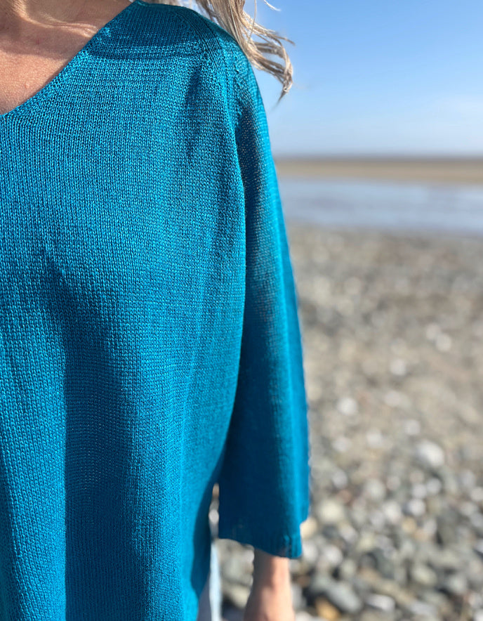 woman wearing turquoise linen knit sweater on the beach