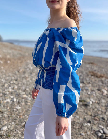 Person wearing a blue and white patterned top on a beach