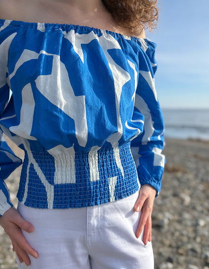 Person wearing a blue and white patterned top on a beach
