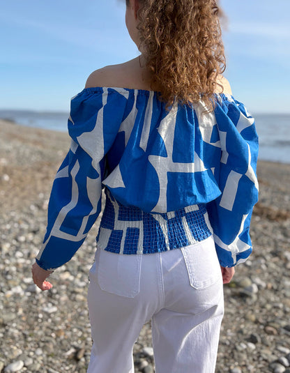 Person wearing a blue and white patterned top on a beach