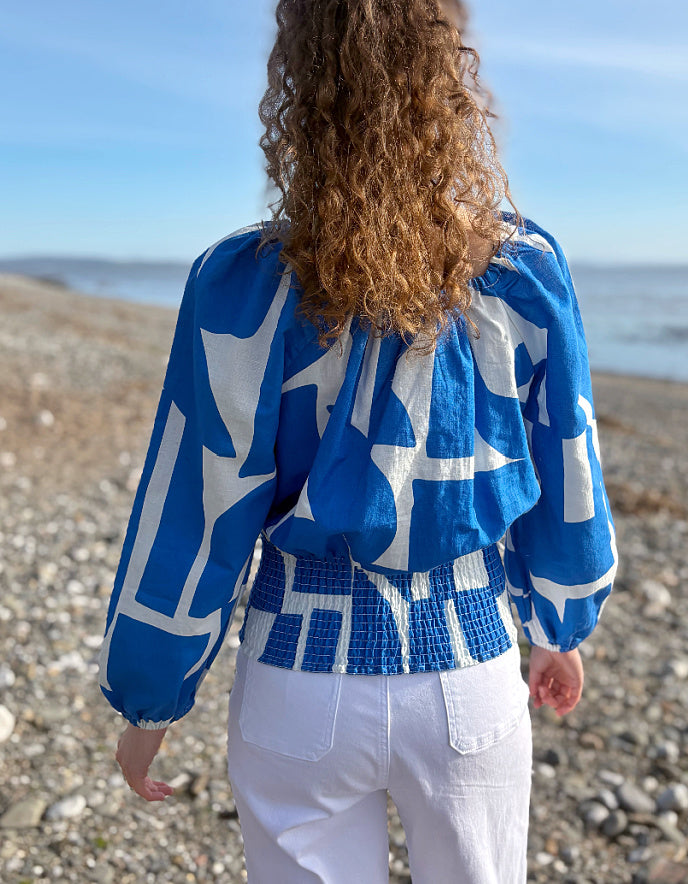 Person wearing a blue and white patterned top on a beach